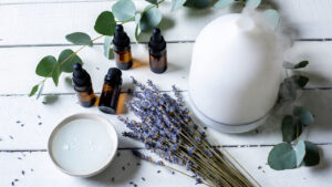 Accessoires aromathérapie bébé : diffuseur ultrasonique et huiles essentielles sur surface en bois blanc