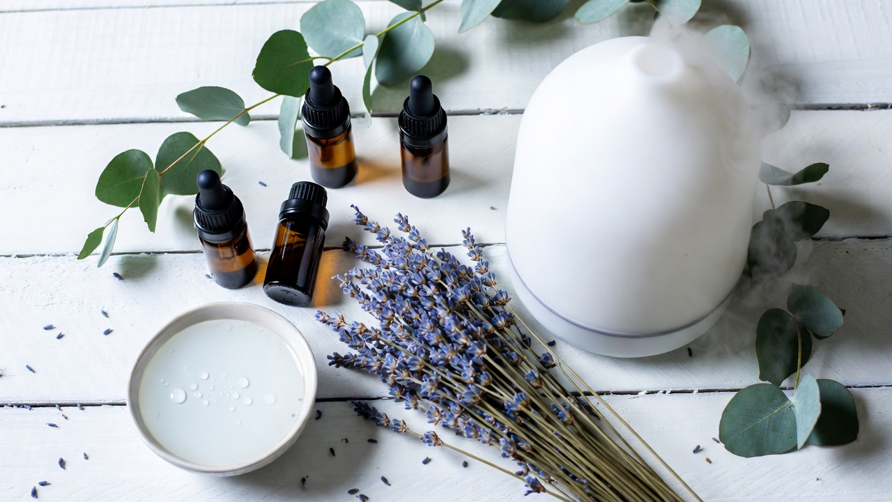 Accessoires aromathérapie bébé : diffuseur ultrasonique et huiles essentielles sur surface en bois blanc